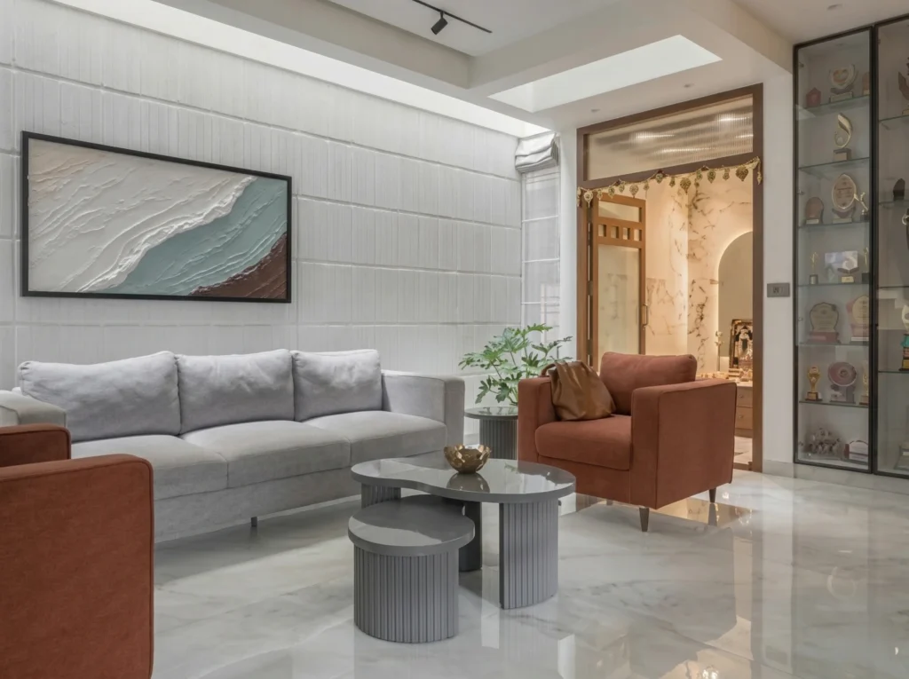 Luxury living room interior featuring a textured white feature wall, rust-colored accent chairs, nested grey coffee tables, and a bespoke glass display cabinet.