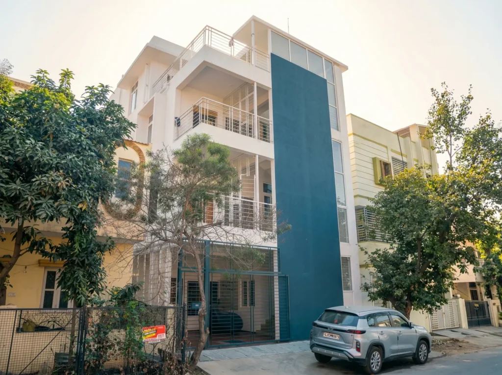 Modern multi-story residential building with a contemporary white and blue facade, spacious balconies with stainless steel railings, and professional turnkey construction.