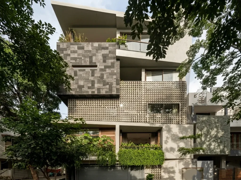 Arun Charanthimath residence – multi-storey front elevation with grey stone mosaic cladding, pyramid-pattern concrete jali facade, cascading balcony greenery, and basement garage by High Tech Constructions, Bangalore