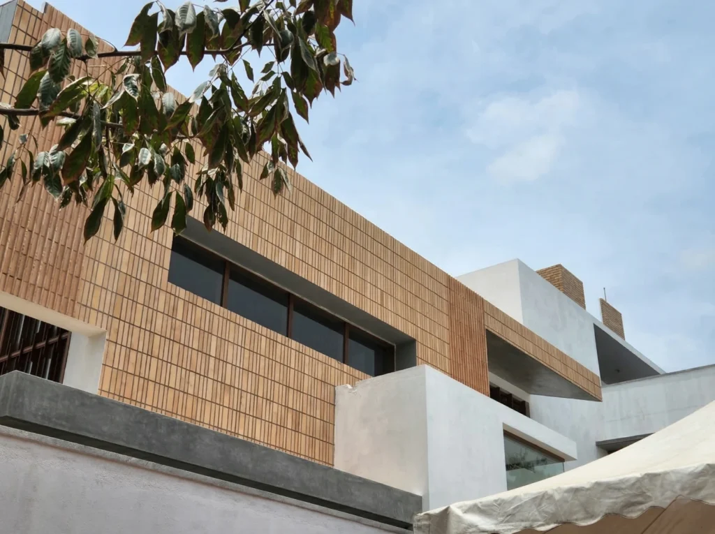 Bharath and Nivya residence – upper floor exterior detail with vertical terracotta tile cladding and exposed concrete frame by High Tech Constructions, Bangalore