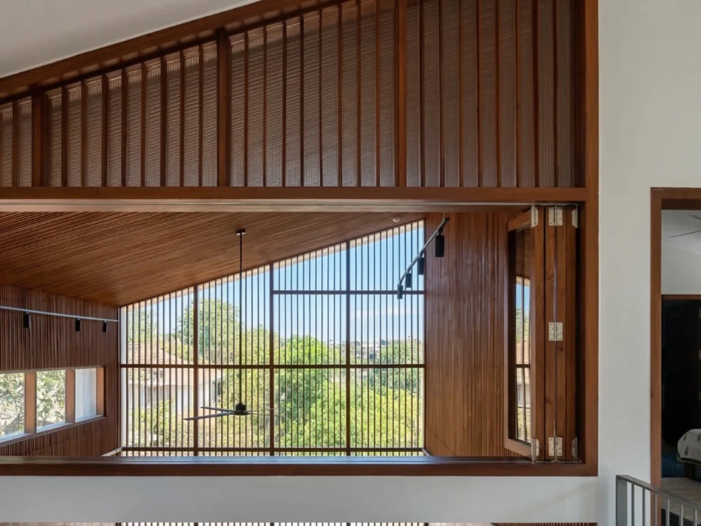 Bharath and Nivya residence – double-height interior with teak wood louvred ceiling and wall screen, angled skylight, and garden view by High Tech Constructions, Bangalore