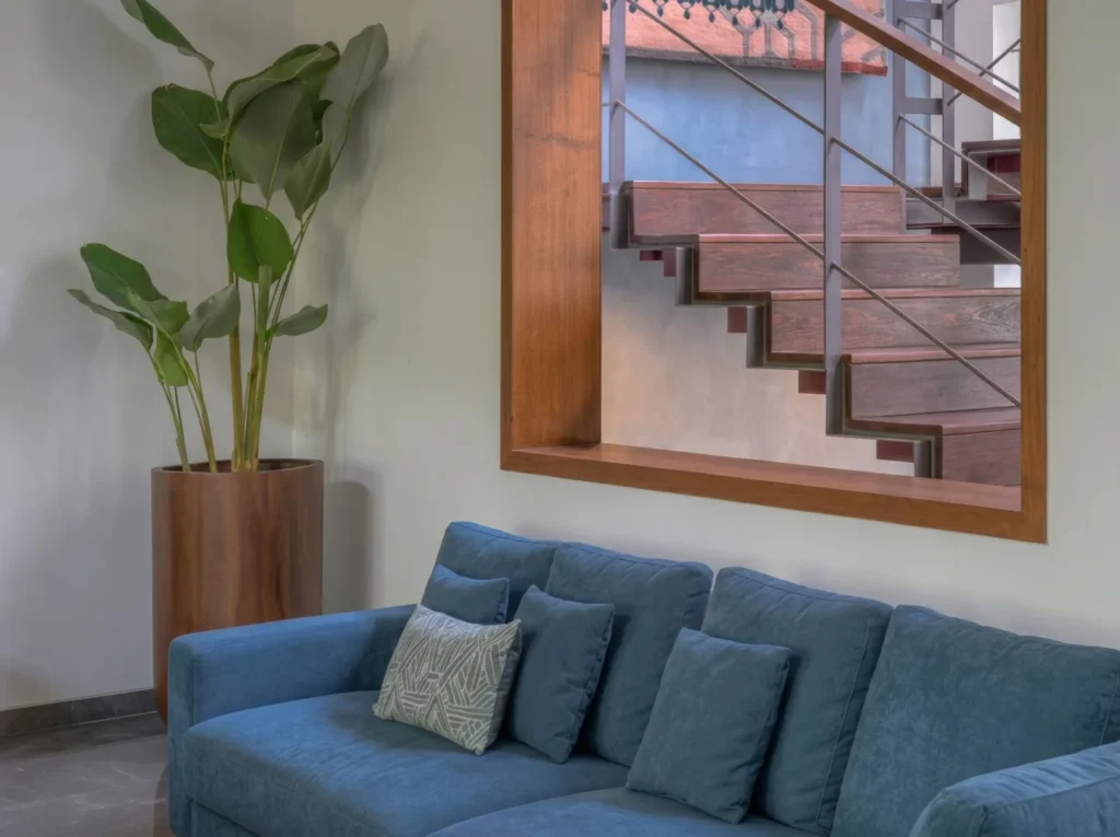 Interior construction detail of a residential living room in Bangalore with a timber-framed staircase window and blue sofa