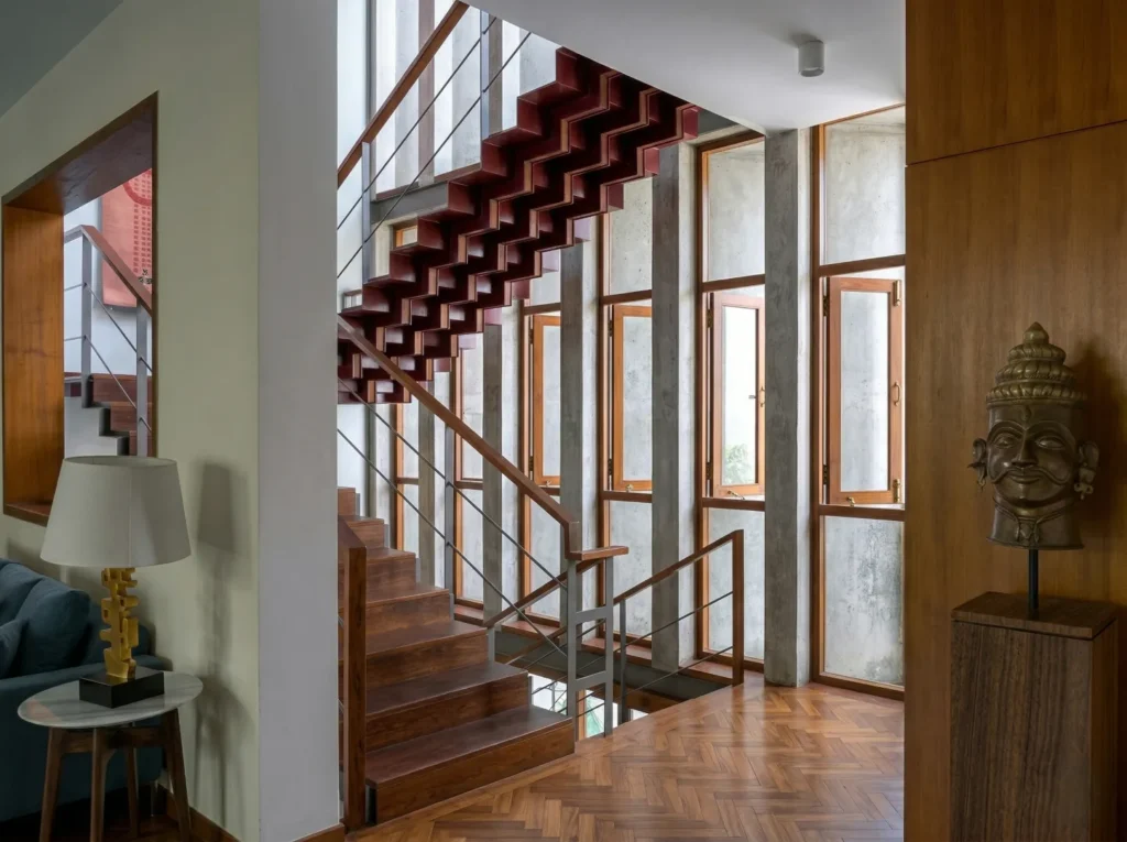 Dramatic floating staircase with crimson treads and herringbone timber floor in a residential home construction in Bangalore