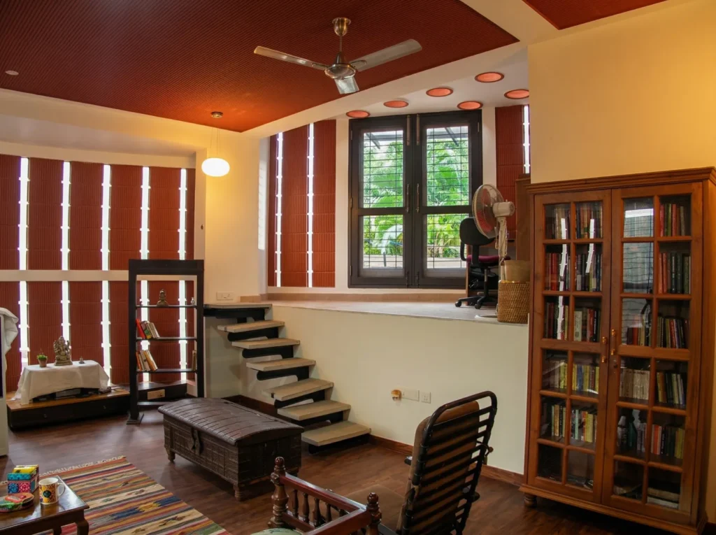 Kalpana turnkey bungalow – library and study room interior with laminated wood flooring, terracotta ceiling, bookshelf, and split-level stairs by High Tech Constructions, Bangalore