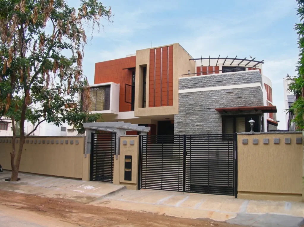 Kalpana turnkey bungalow – street-facing front elevation with stone cladding, terracotta panels, and horizontal steel gate by High Tech Constructions, Bangalore