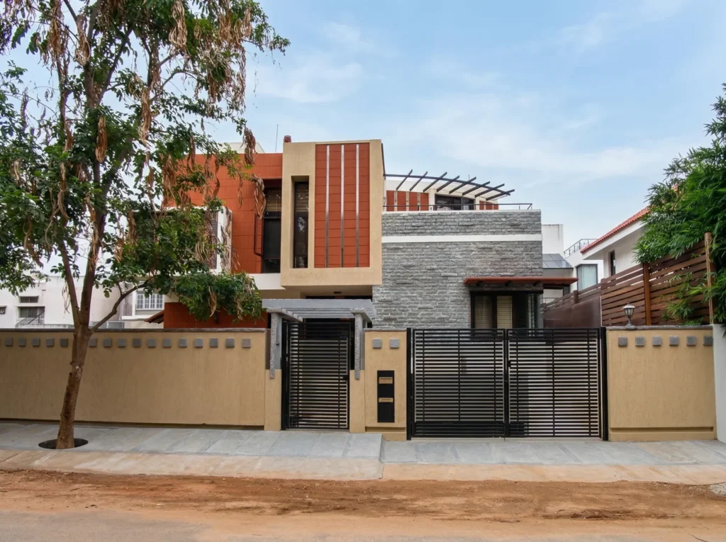 Kalpana turnkey bungalow – completed front elevation with granite stone facade, terracotta cladding, compound wall, and main entrance gate by High Tech Constructions, Bangalore