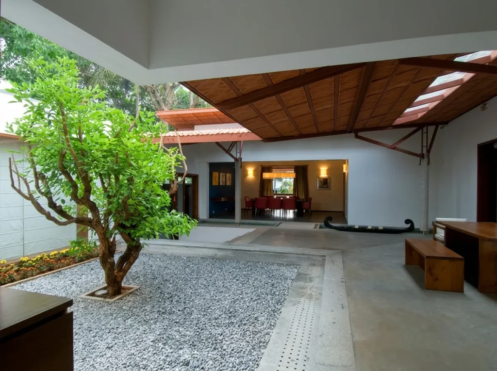 Traditional courtyard home construction in Bangalore with gravel garden, terracotta tile roof, timber ceiling, and open living pavilion