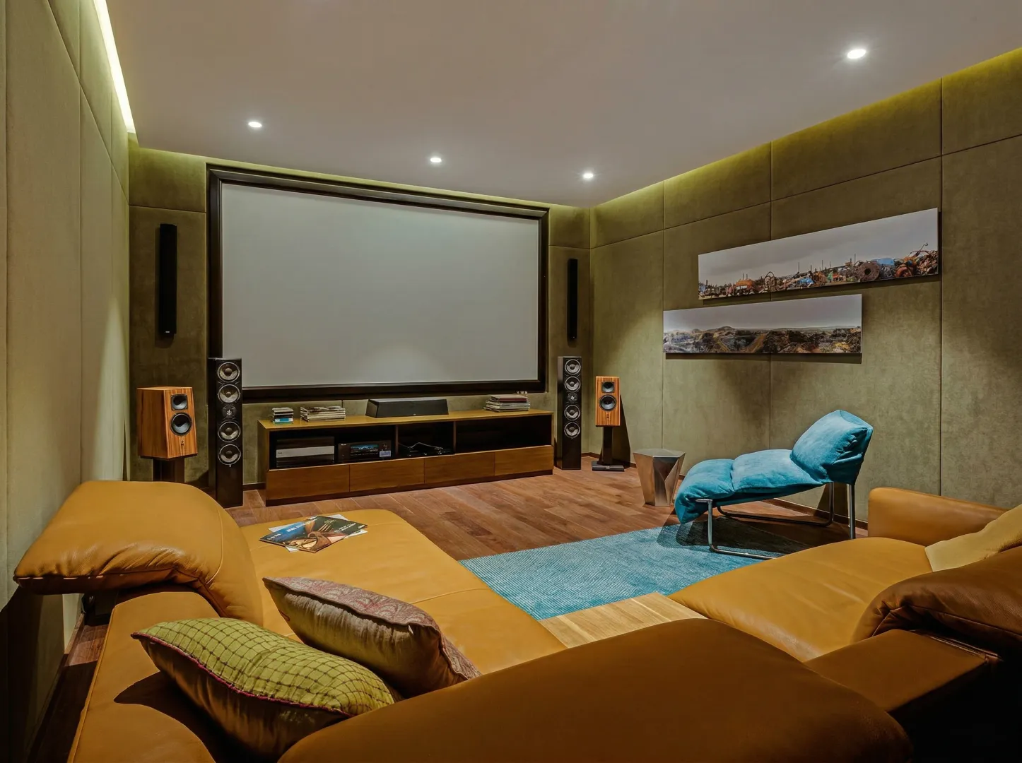 Luxury home theatre interior construction in Bangalore with olive upholstered walls, leather recliner sofas, and large projection screen by High Tech Constructions