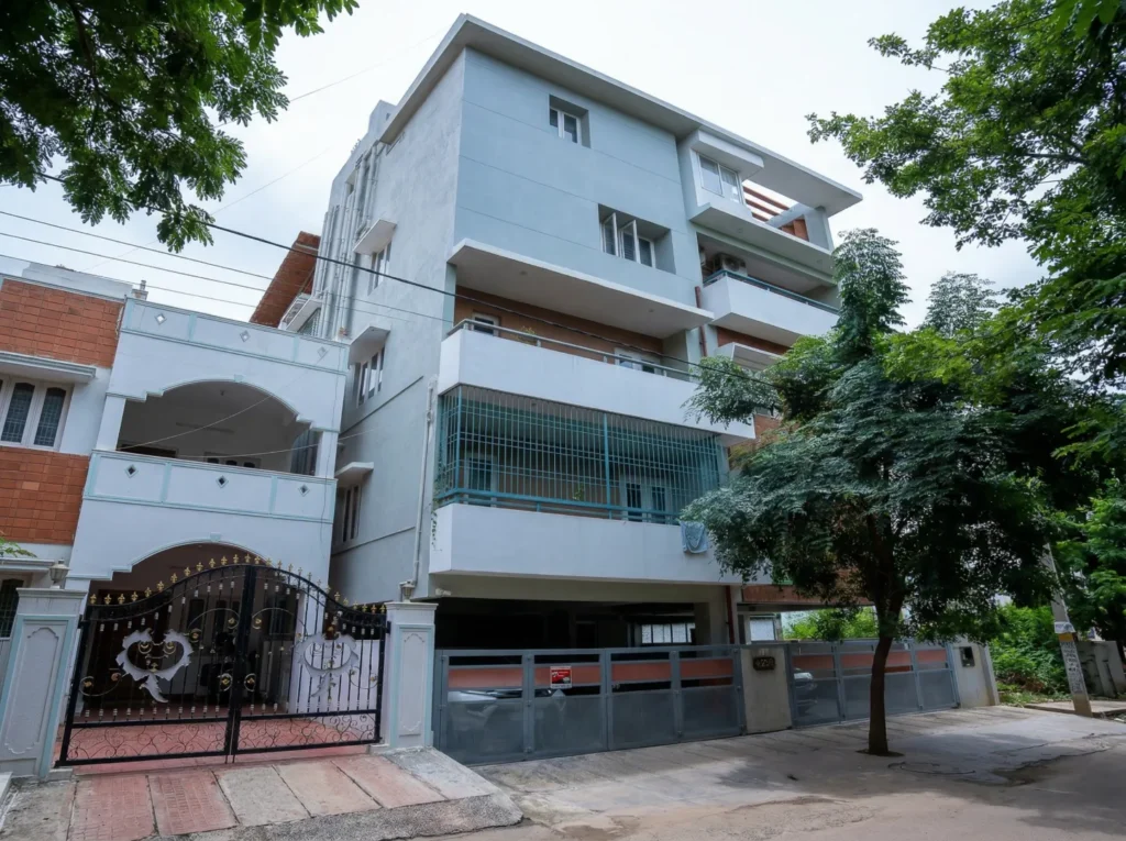 Multi-storey white residential building with ornate gate and stilt parking — residential building project in Bangalore.