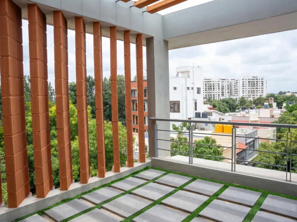 Landscaped rooftop terrace with terracotta louvre columns, turf pathway, and city views — residential construction in Bangalore.