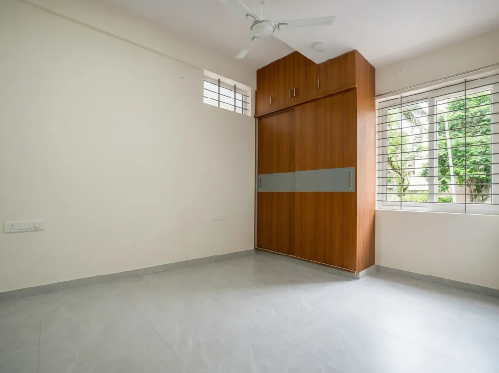 Guest bedroom interior featuring a grey wood-finish sliding wardrobe with open shelving and white minimalist walls.