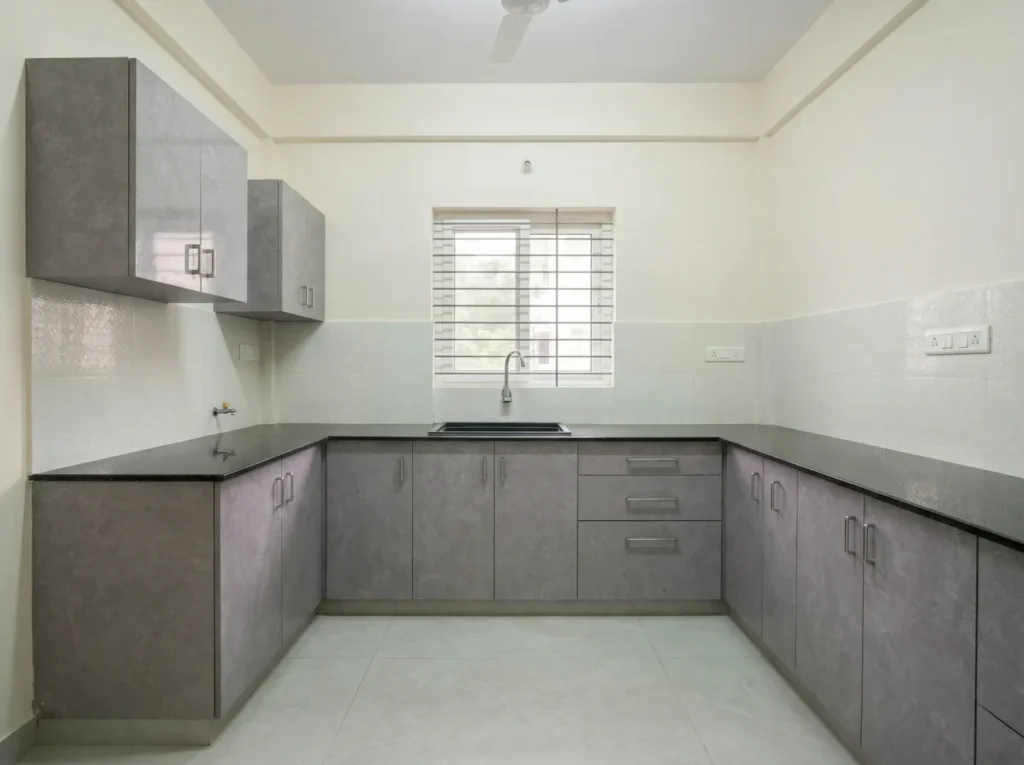 Modern U-shaped modular kitchen with grey textured cabinetry, black granite countertops, and efficient space-saving design.