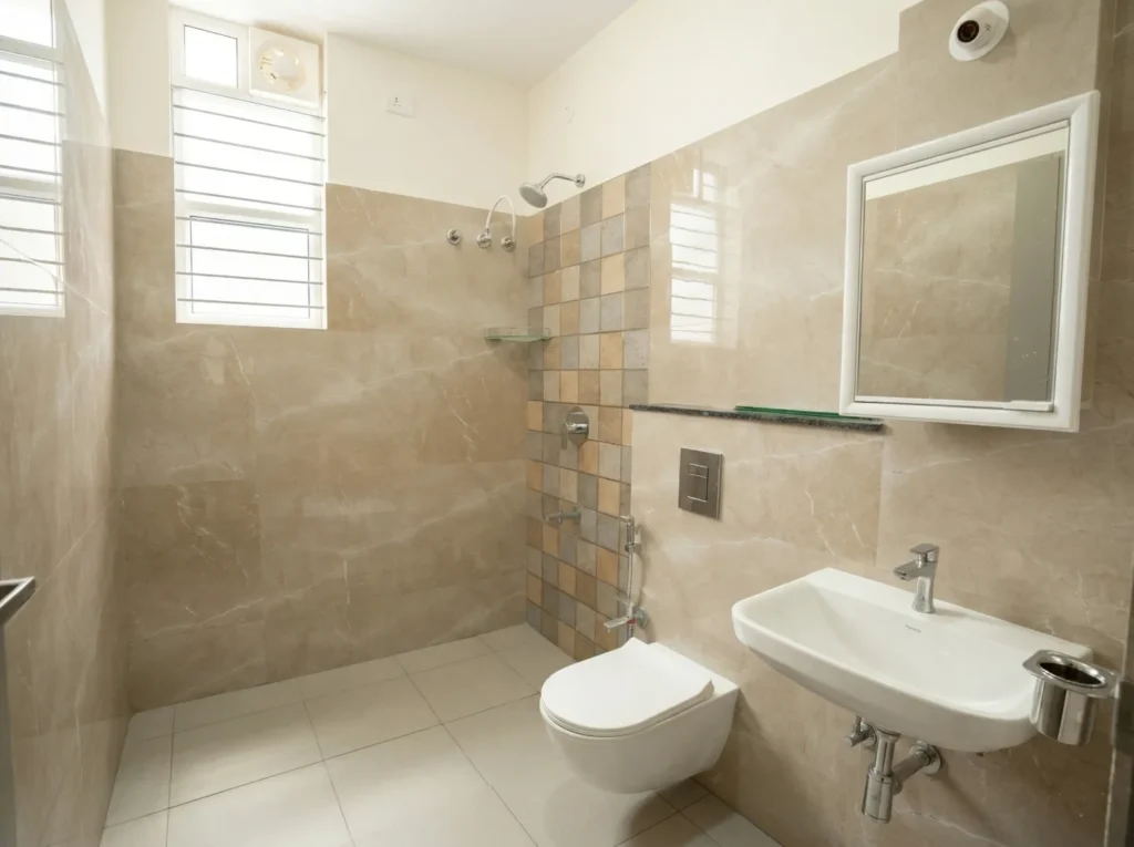 Modern bathroom design with beige marble-finish wall tiles, a wall-mounted commode, and premium sanitary fittings.