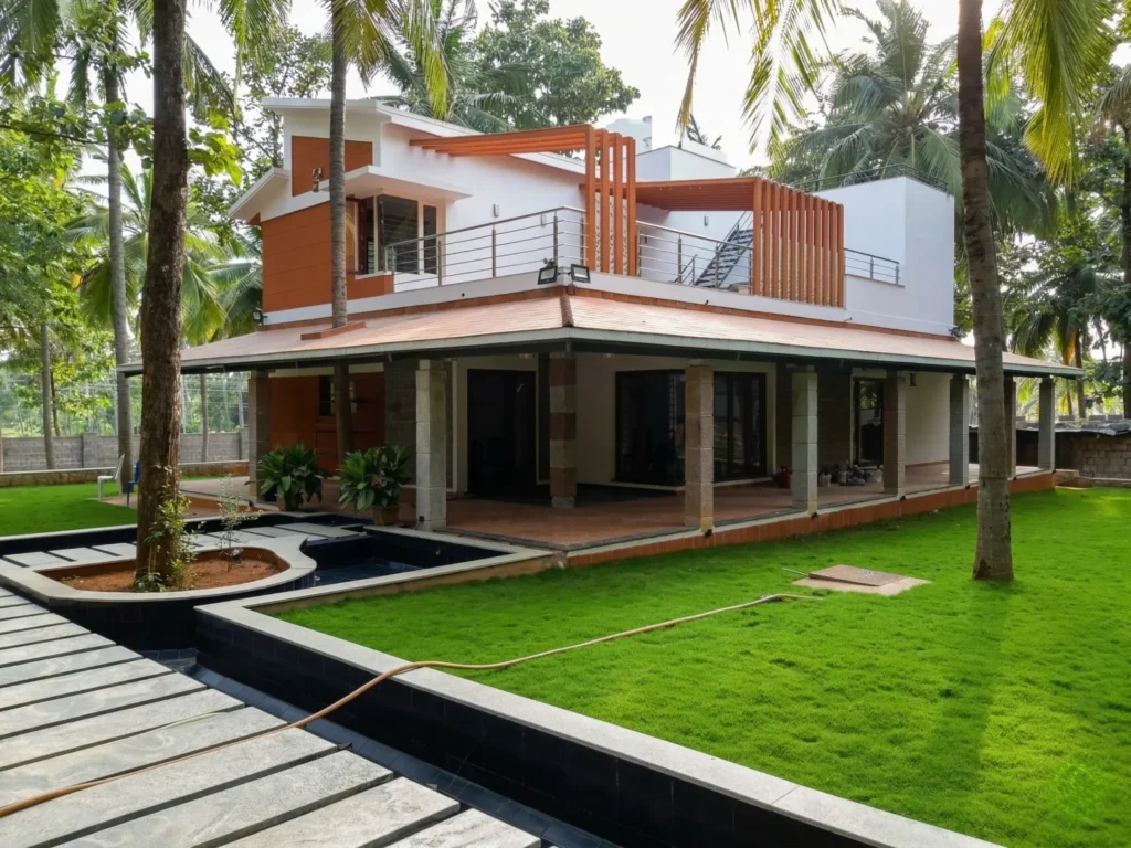 Luxury farm house exterior design with an L-shaped granite walkway, manicured lawn, and an integrated outdoor water feature or pond.