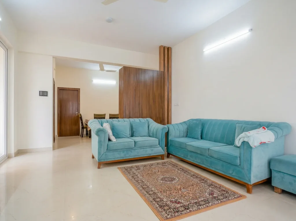 Spacious living room with plush teal sofas and wooden partitions by High Tech Constructions.