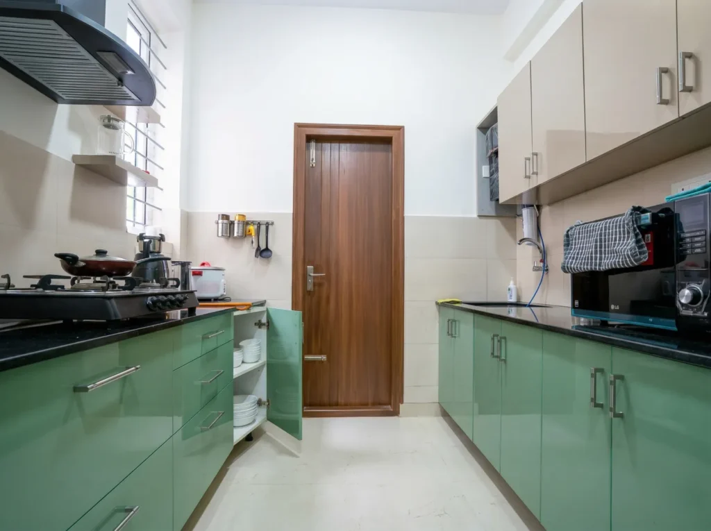 Modern modular kitchen with green cabinetry and black granite countertop in a home construction site.