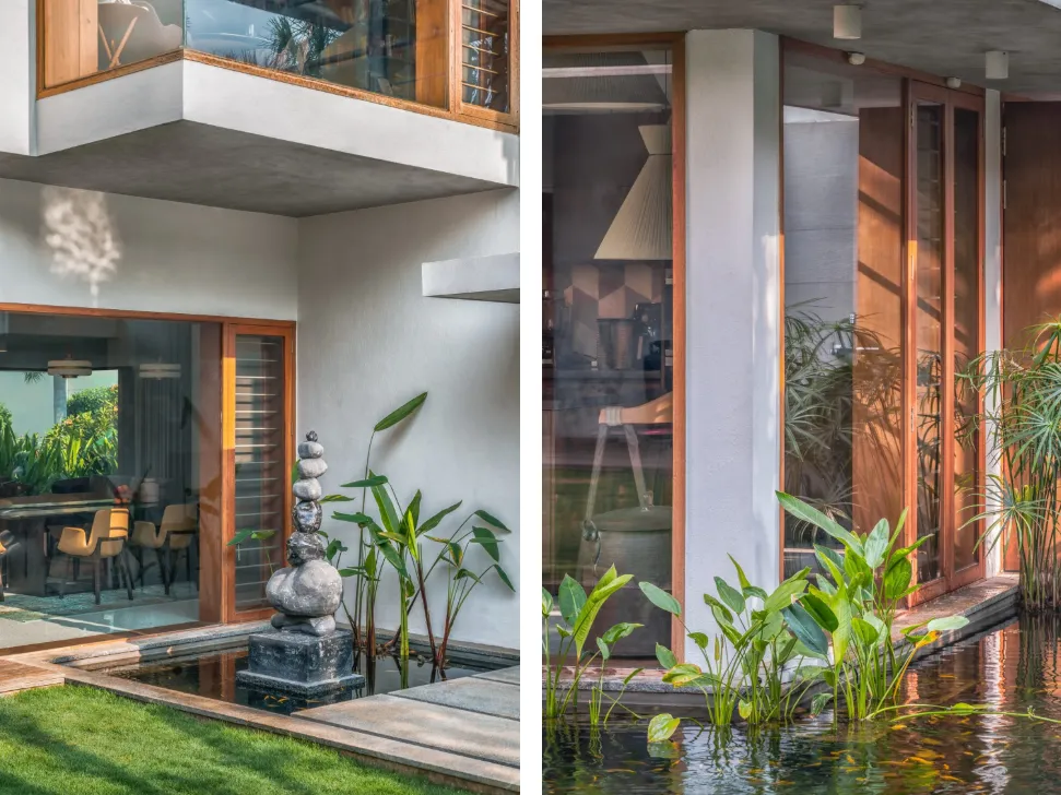 Residential home construction in Bangalore with koi pond courtyard, stacked stone sculpture, teak-framed glazing, and tropical planting by High Tech Constructions