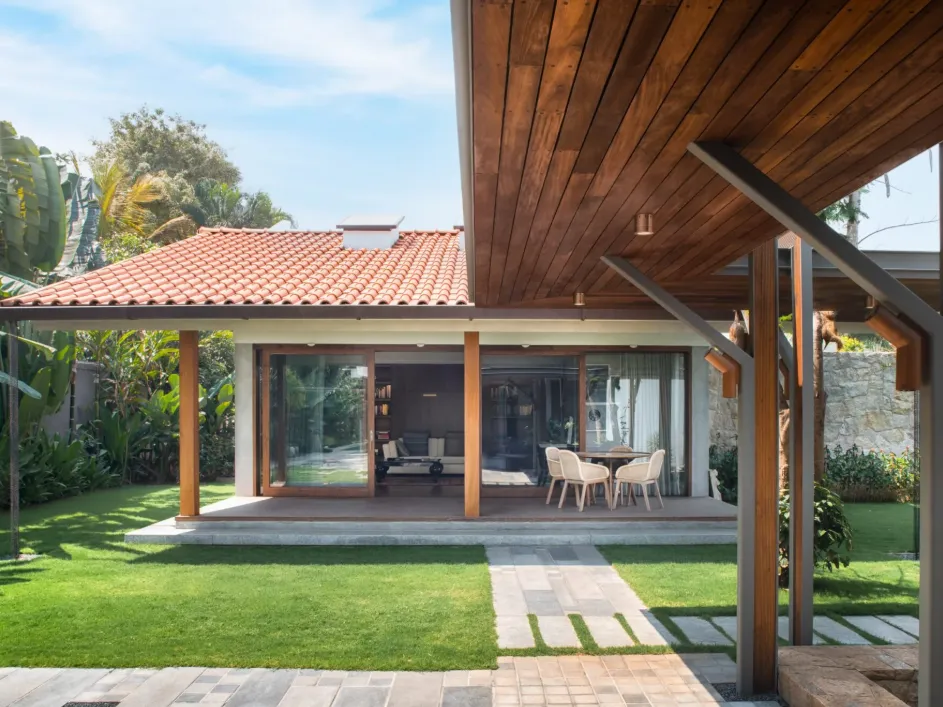 Residential garden pavilion with terracotta tile roof, teak timber ceiling, outdoor dining terrace, and lush tropical garden in a Bangalore home construction by High Tech Constructions