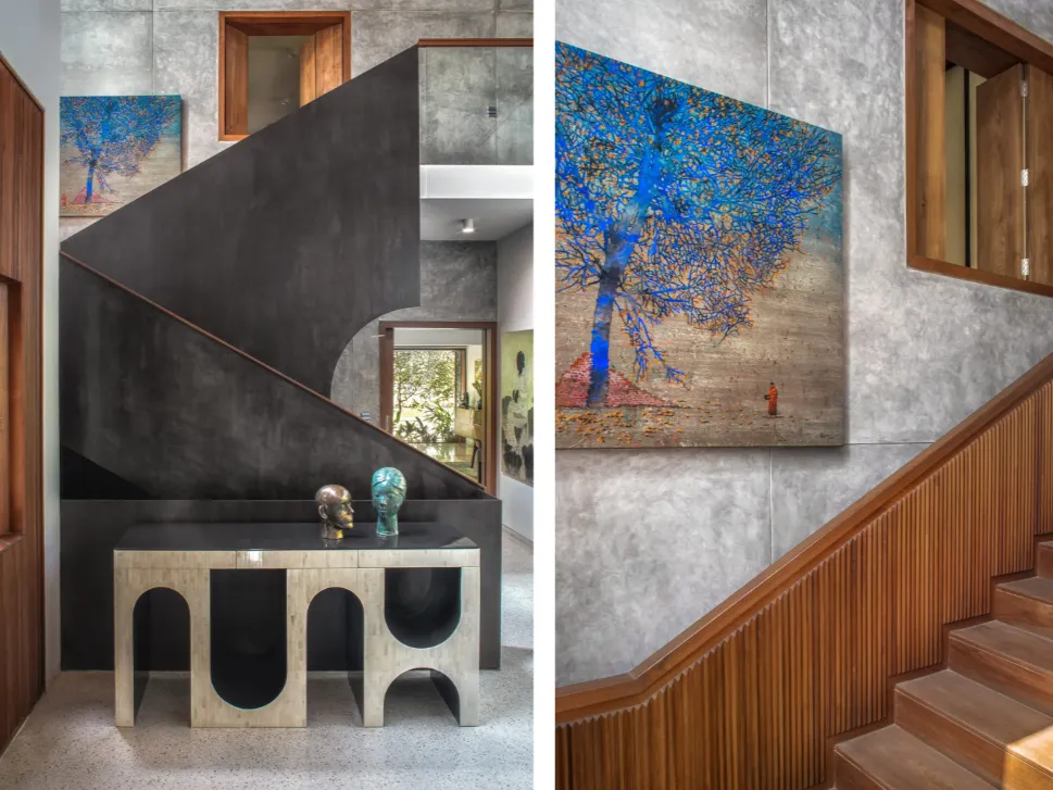 Residential staircase hall with dark steel stringer, terrazzo floor, bronze sculptures, and large-scale art in a Bangalore home construction by High Tech Constructions