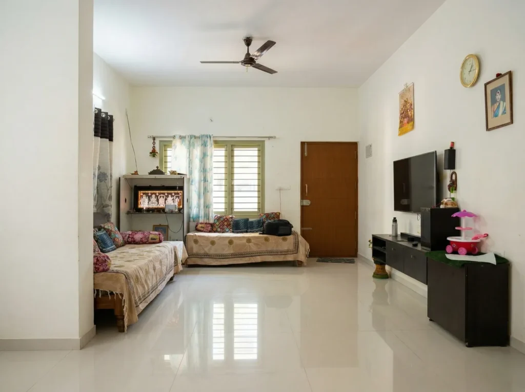 Spacious open-concept living room interior with high-gloss vitrified tile flooring, natural ventilation, and minimalist residential electrical fittings.
