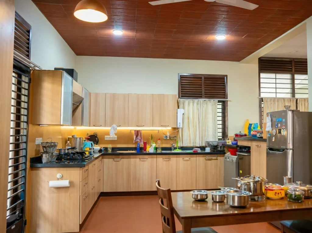 Anand Prakash residence – modular kitchen with terracotta filler slab ceiling, wood-finish cabinets, granite countertop, and teak louvred windows by High Tech Constructions, Bangalore