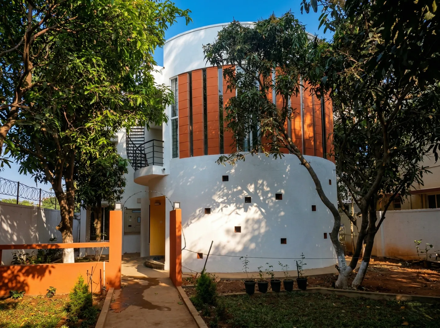 Modern eco-friendly home design with a curved exterior, sustainable terracotta cooling vents, and professional landscape integration.