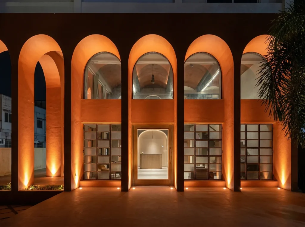 Dramatic night-lit restaurant facade with terracotta arches and warm uplighting in a Bangalore commercial construction by High Tech Constructions