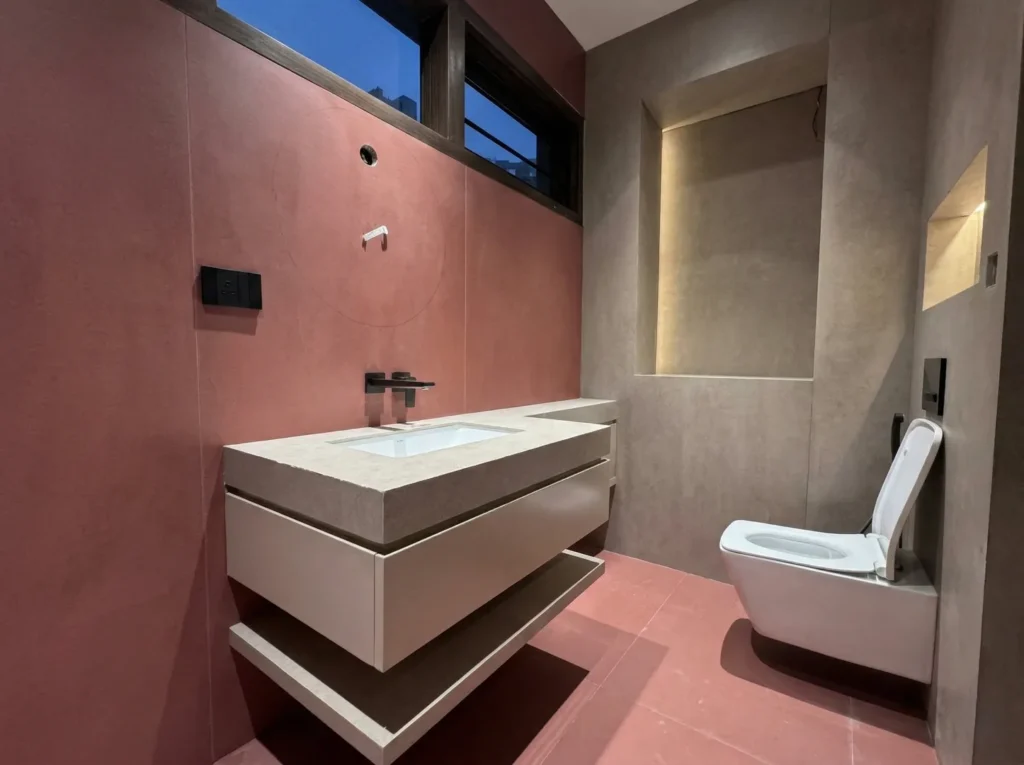 Modern residential bathroom interior construction in Bangalore with terracotta walls, floating vanity, and wall-hung WC by High Tech Constructions