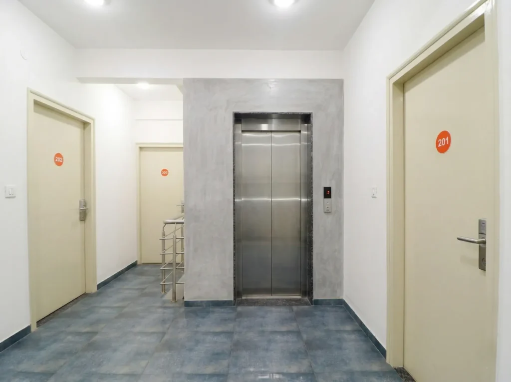 Contemporary elevator lobby with grey texture wall and tiled flooring by High Tech Constructions.