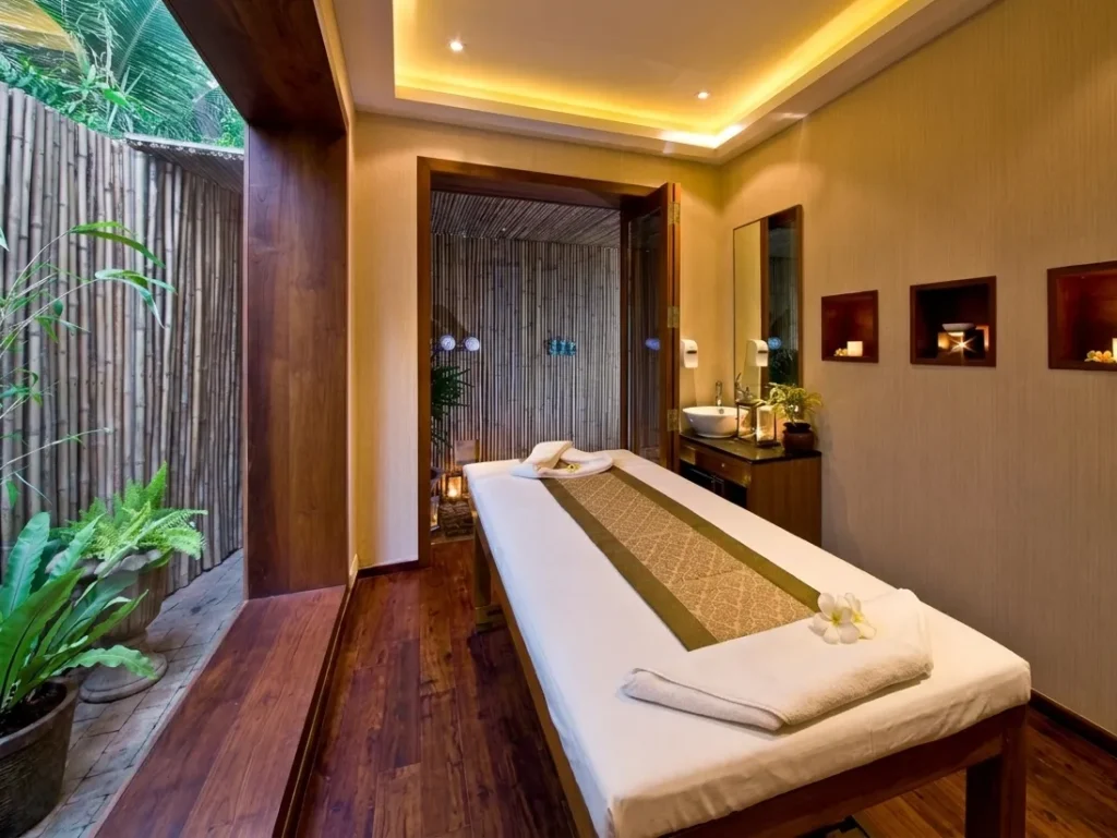 Luxury spa treatment room interior construction in Bangalore with massage table, bamboo garden wall, and warm cove lighting by High Tech Constructions