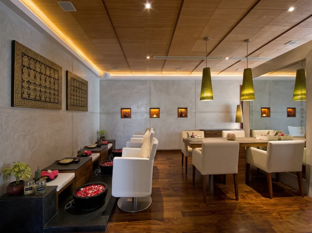 Commercial spa pedicure and manicure lounge interior construction in Bangalore with timber ceiling, floral foot basins, green pendants, and traditional artwork by High Tech Constructions