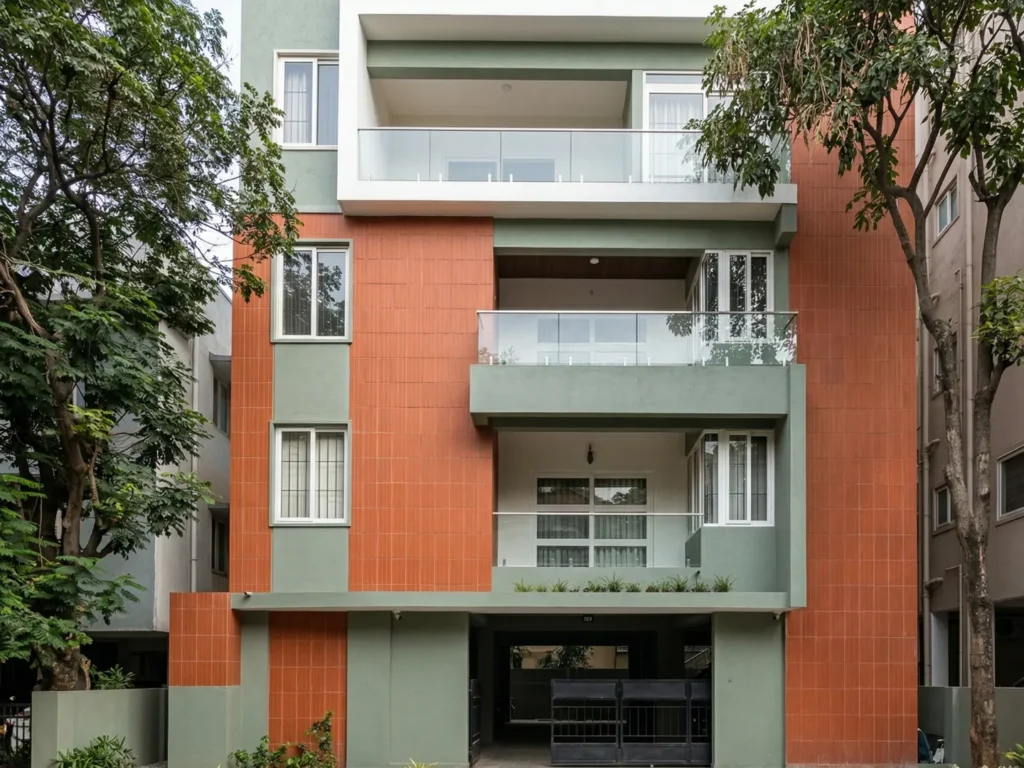 Sugandha multi-storey residential building with terracotta tile cladding, sage green finish, and glass balcony railings in Bangalore.